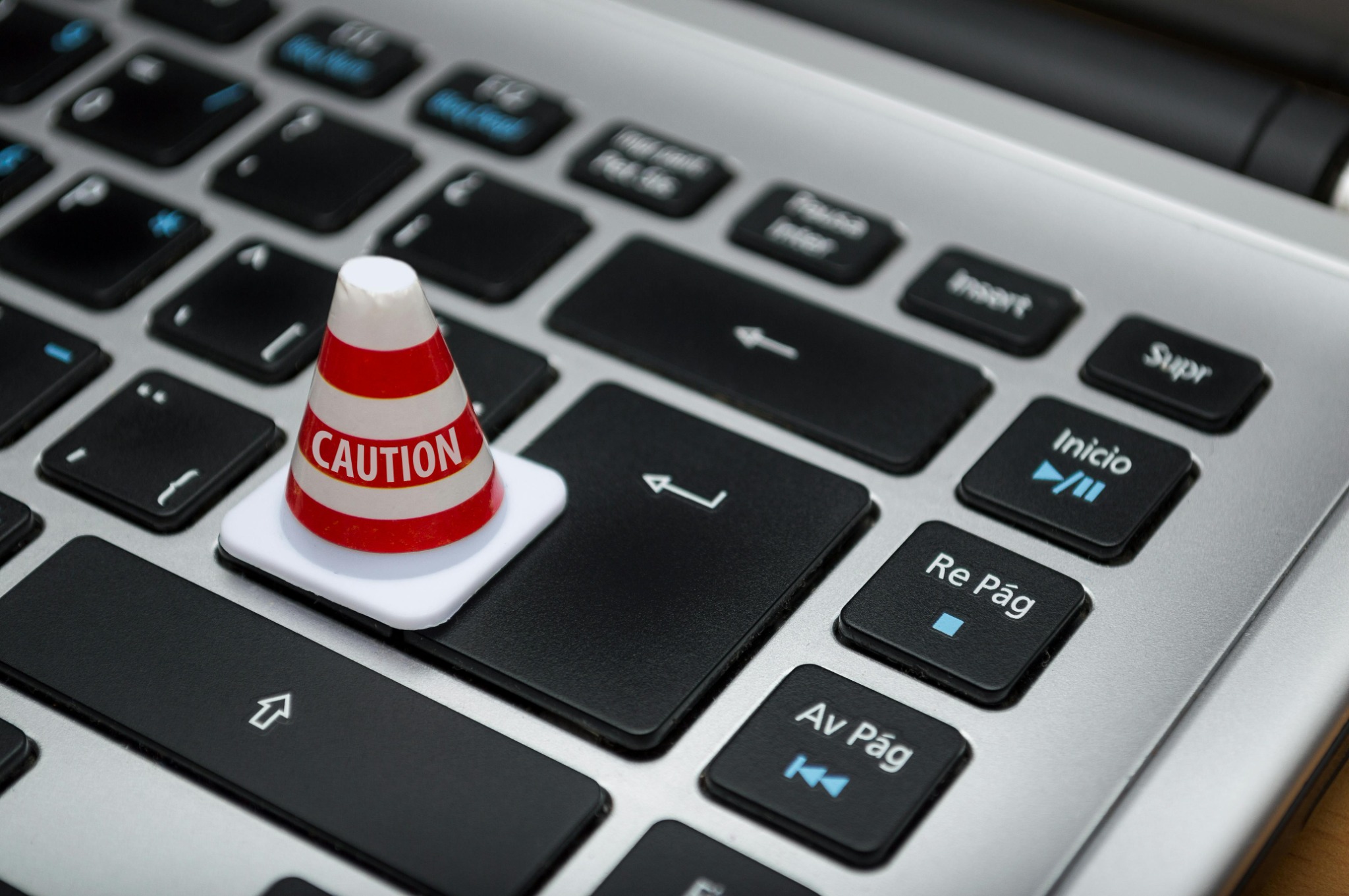 A small caution cone labeled 'Caution' placed on a keyboard key, symbolizing caution with hidden webshells.